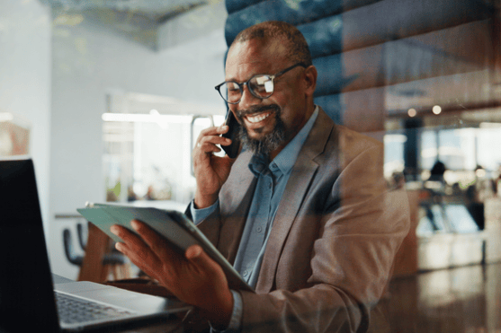 Man on phone observing ipad at desk