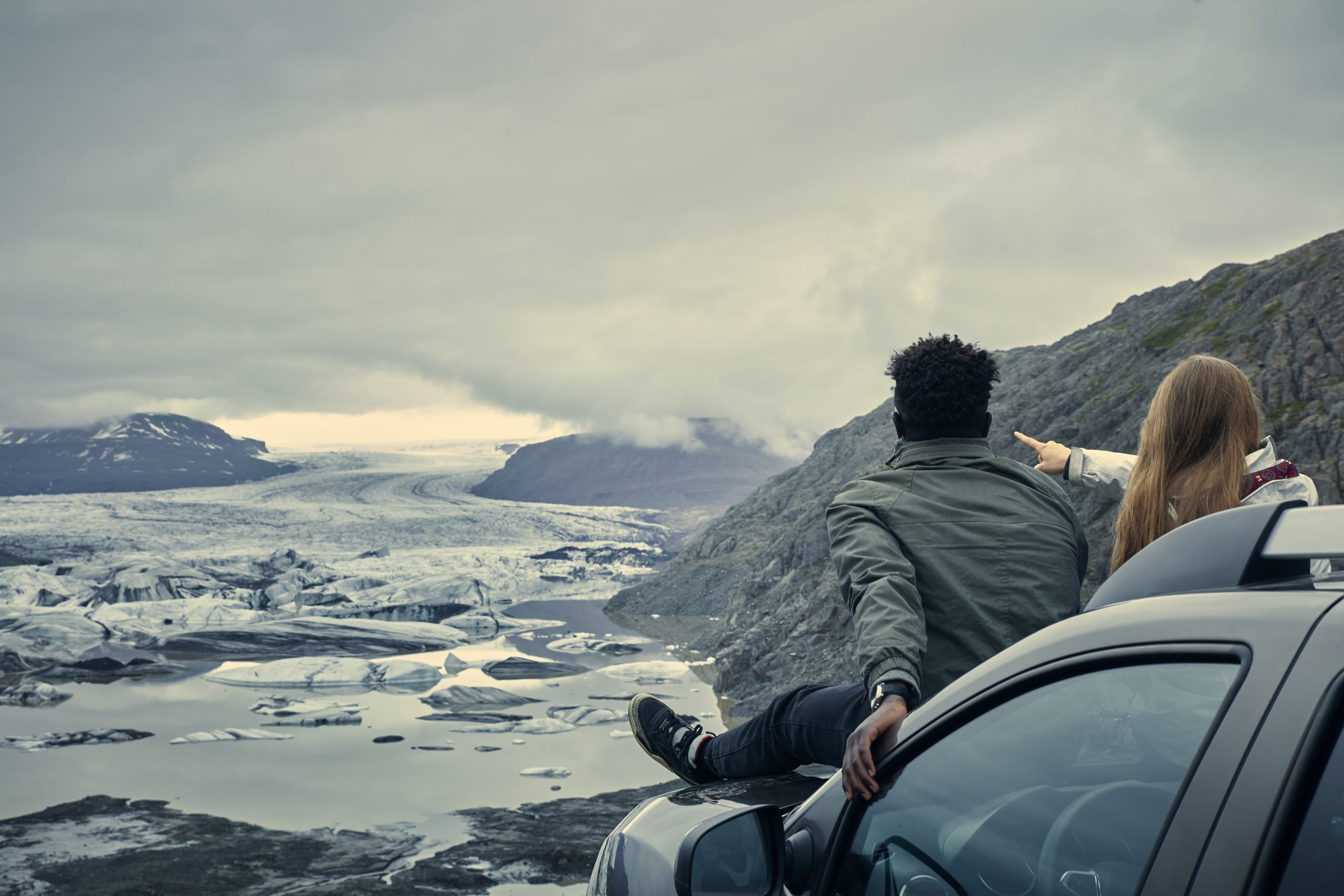 Multi ethnic couple enjoying glacier lagoon from car mask